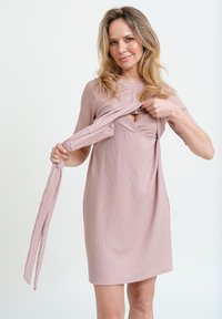 Rippiges, hellrosa Kleid mit kurzen Ärmeln, das über eine Knoten-Details an der Taille und ein offenes Panel an der Brust verfügt. Weicher Stoff.
