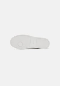 Hvid sneakersål med tekstureret gummi, afrundet form og centralt cirkulært logo. Glat materiale og minimalistisk design.
