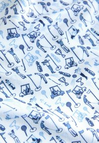 Weißer Stoff mit einem sich wiederholenden Muster von blauen Golfmotiven, darunter Spieler, Golftrolley, Trophäen und Fahnen.