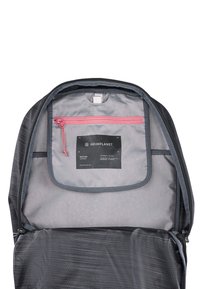 Interior de mochila negra con un forro gris, un bolsillo con cremallera rosa y una etiqueta que muestra "HEIMPLANET MOTION SERIES" con patrones geométricos.