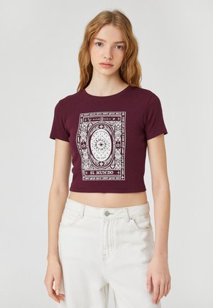 Bordeauxrood crop t-shirt van ribstof met een wit grafisch patroon waarop de tekst "EL MUNDO" en een oogmotief staat.