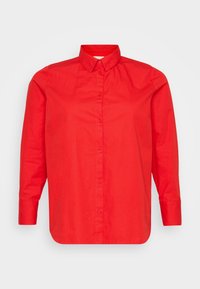 Camicia rossa a maniche lunghe con colletto a punta e orlo dritto, esposta su uno sfondo bianco uniforme.