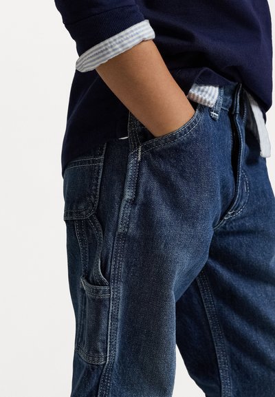 Jeans de ganga azul escuro com bolsos laterais, detalhes de costura sutis e um ajuste confortável com um design clássico.