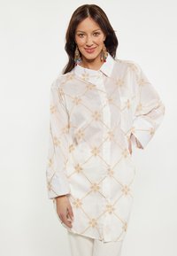 Witte overhemden met lichtgouden geometrische borduursels, lange mouwen en een borstzak, met een kraag en een zachte textuur.
