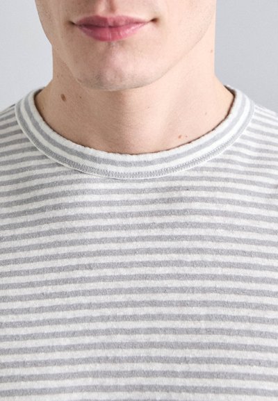 Camiseta de rayas en gris claro y blanco con cuello redondo, hecha de una tela suave. Las rayas son finas y están espaciadas de manera uniforme.