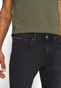 Svart denimjeans med slim fit, med en klassisk femficksdesign, metallknappstängning och flerfärgad sömdekoration.