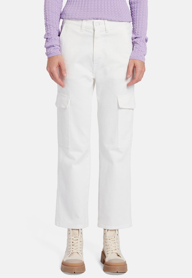 Pantaloni cargo bianchi con tasche laterali, taglio dritto, realizzati in denim. Abbinati a un top viola testurizzato e stivali beige con lacci.