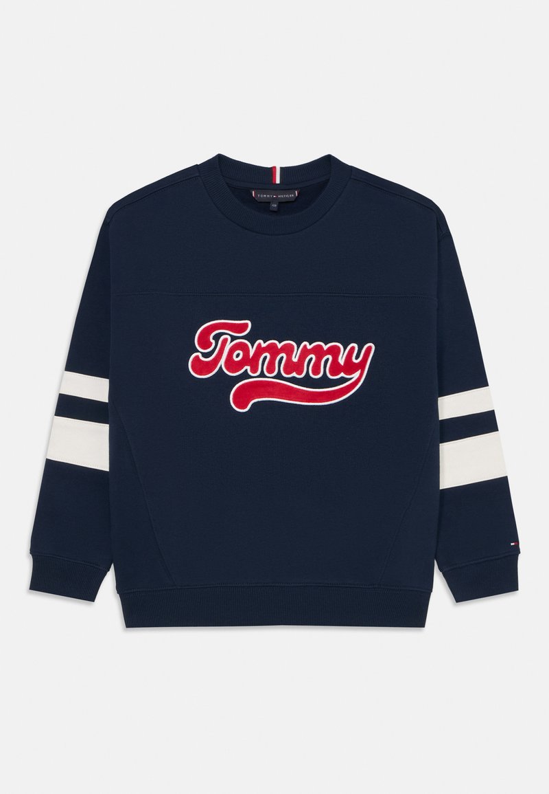 Mörkblå sweatshirt med en vit och röd broderad "Tommy"-logotyp. Har vita ränder på ärmarna samt ribbade mudd och krage.