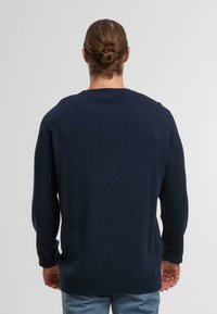 Maglione a maglia blu navy con collo a giro, polsini e orlo a coste, caratterizzato da una texture liscia e un design a vestibilità regolare.