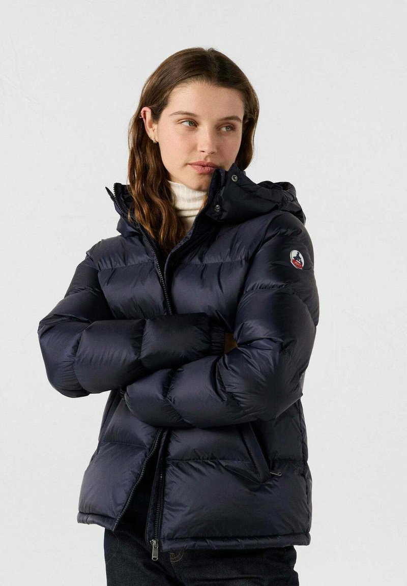 Chaqueta acolchada azul marino con capucha, diseño acolchado, cremallera frontal, puños elásticos y detalle de logo en la manga. Material suave y brillante.