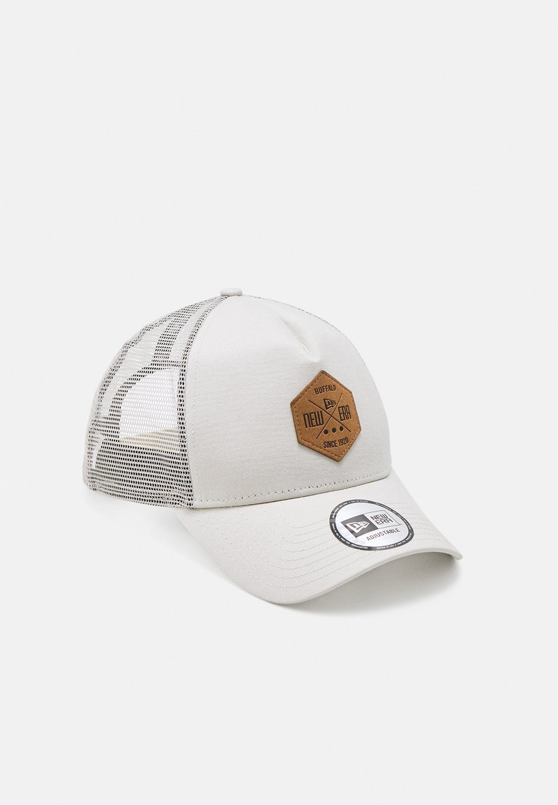 Boné cinza claro com aba curva, painéis de malha e um retângulo de couro castanho em forma hexagonal com a marca "New Era". Inclui etiqueta ajustável em forma circular.