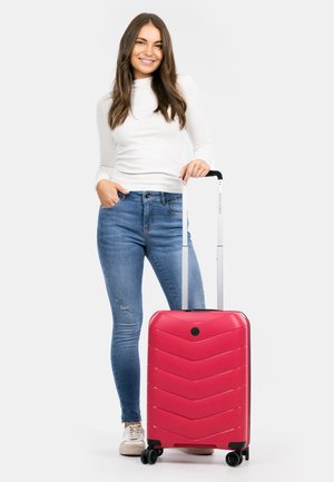 Roter Hartschalenkoffer mit Chevron-Muster, schwarzen Akzenten, ausziehbarem Griff und vier Rollen. Strapazierfähiges Material mit einem eleganten Design.