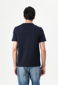 Marineblå bomull T-skjorte med korte ermer, rund hals og en ren bakdesign, kombinert med lyseblå denimjeans.