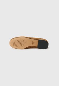 Chaussure à motifs marron en imprimé léopard avec une tige en tan texturé et un talon en caoutchouc noir. Dispose de rainures pour l'adhérence et de trous de ventilation.