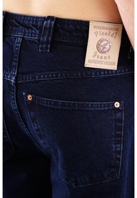 Dunkelblaue Jeans aus Denim mit einem Patchlabel mit "Picaldi" Branding. Enthält Kupfennieten und zwei Gesäßtaschen.