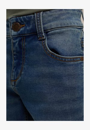 Jeans de mezclilla azul con costuras naranjas, que cuentan con un bolsillo frontal y un cierre de botón metálico en la cintura. Diseño clásico de cinco bolsillos.