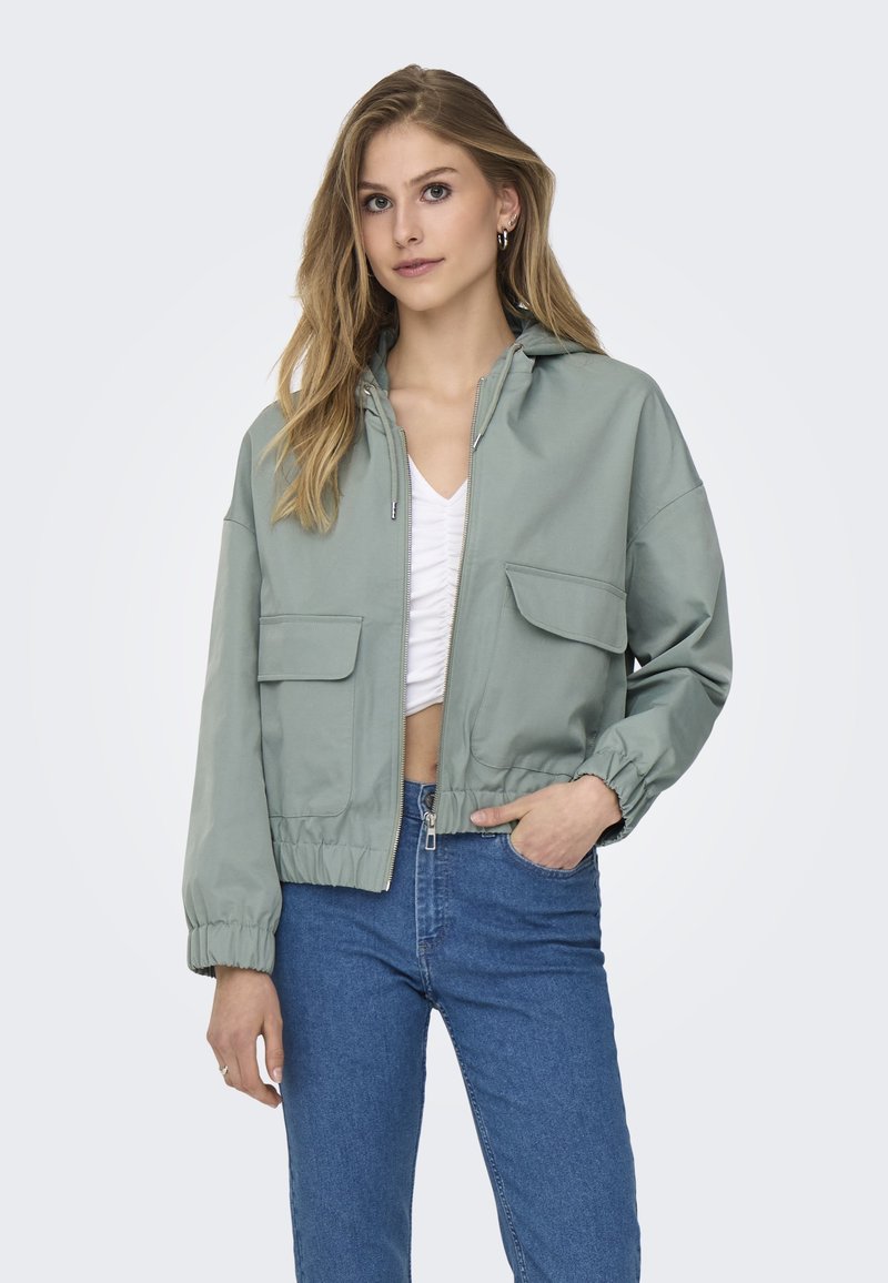 Lys grøn cropped jakke med hætte, front lynlås og to frontlomme med klap. Har elastiske manchetter og nederkant. Tekstureret, afslappet design.