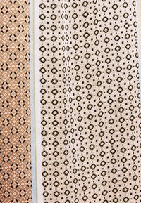 Textil med en blandning av geometriska mönster i brunt, krämfärgat och svart. Designen innehåller hexagoner och små blommor över tre segment.