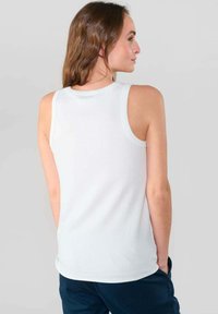 Witte geribbelde tanktop met een ronde halslijn en mouwloos ontwerp. Glad textuur, nauwsluitende snit en langere achterkant.
