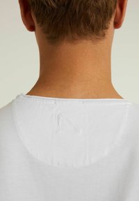 Tricou alb din bumbac, cu decolteu rotund, având un mic detaliu cu logo brodat la spate. Textură moale și design casual.