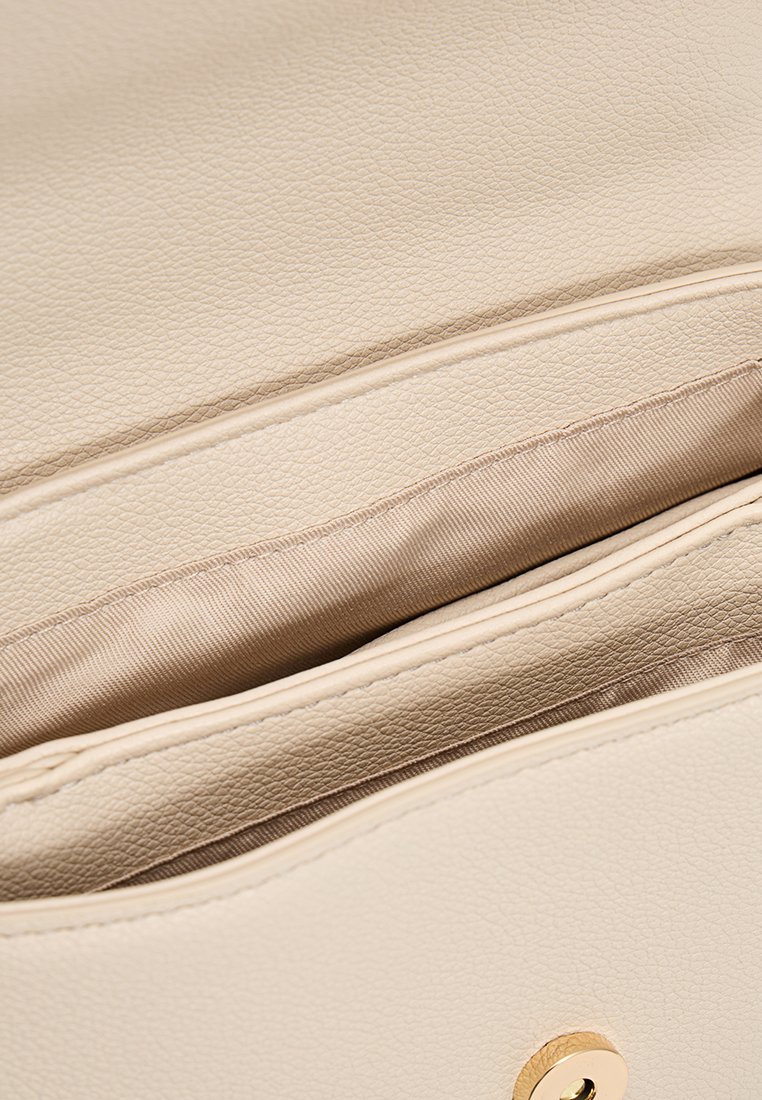 Lichtbeige leren tas interieur met een gladde textuur, voorzien van twee zakken en een beige voering. Gouden beslag op de sluiting.