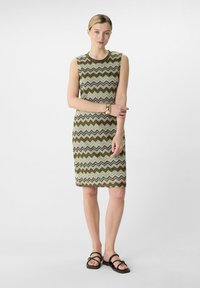 Sukienka dzianinowa z wzorem w zygzaku w kolorach oliwkowym, kremowym i brązowym. Bez rękawów, okrągły dekolt, długość do kolan.