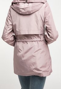 Veste rose clair, résistante à l'eau, avec une taille cintrée, capuche et texture lisse. Présente un design court et des poignets élastiques.