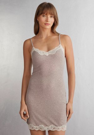 Zachte beige cami-jurk met kantafwerking bij de halslijn en zoom, voorzien van dunne verstelbare bandjes en een aansluitende pasvorm. Gladde textuur.