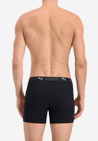 Schwarze Boxershorts mit einem weichen elastischen Bund, der mit weißem Puma-Logo versehen ist, im engen Schnitt, mit glatter Textur und kurzen Beinen.