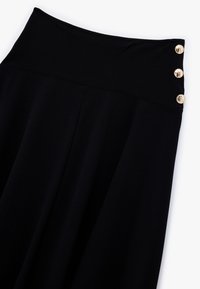 Pantalones de pierna ancha negros con una cinturilla alta que presenta tres botones dorados en un lado. Tejido suave con una textura delicada.