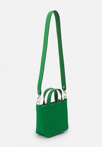 Vihreä tikattu käsilaukku, jossa on kaksi yläkahvaa ja pitkä säädettävä olkahihna. Laukussa on vetoketjullinen suljenta ja teksturoitu pinta.