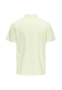 Polo de manga corta en amarillo claro, hecho de algodón, con cuello tipo polo y una textura suave sin patrones ni acentos visibles.