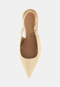 Chaussure à talon en cuir verni beige avec un bout pointu, des côtés découpés et un accent de boucle métallique. Texture lisse avec une forme d'amande.