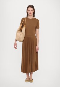 Robe brune à manches courtes avec une jupe plissée ; associée à un sac texturé beige et des chaussures à plat dorées. La robe a une taille cintrée.