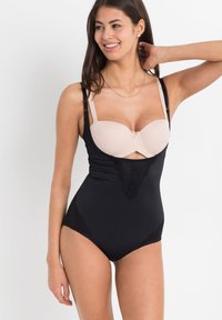 Body nero con parte superiore a reggiseno imbottita color carne, con dettagli in pizzo lungo la parte anteriore. Spalline regolabili e tessuto morbido per il massimo comfort.