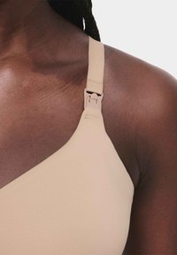 Bra in morbido tessuto beige con design a forma di V, spallina regolabile con un gancio in plastica e superficie senza cuciture.