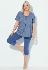 Top azul con estampado, de manga corta y escote en V, combinado con leggings azul cortos. Tejido suave con un corte holgado y una sutil textura.