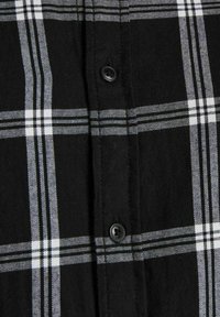 Camicia a quadri bianco e nero con tessuto in cotone, dotata di bottoni in plastica nera e motivi a strisce orizzontali e verticali.