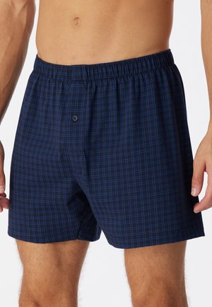 Boxer blu navy a quadri con vita elastica, caratterizzati da linee grigie chiare e un bottone singolo sul davanti.