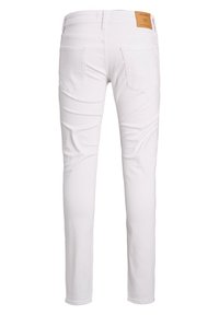 Bílé slim-fit džíny zobrazené ze zadní strany s dvěma zadními kapsami a hnědou značkovou nášivkou na pásku.