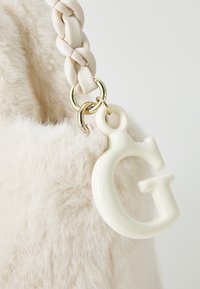 Sac en fausse fourrure ivoire avec une anse crème tressée. Doté d'un charm en forme de lettre "G" blanche brillante et d'accents en métal doré.