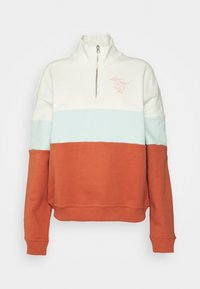 Färgbrokad sweatshirt med hög krage och halvdragkedja. Den har creamfärgade, ljusblå och rostfärgade sektioner med broderad logodetalj.