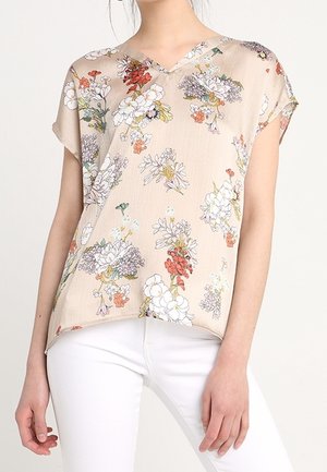 Beige blomsterbluse med korte ærmer, V-udskæring og et let stof. Har farverige blomster mønstre i forskellige nuancer.