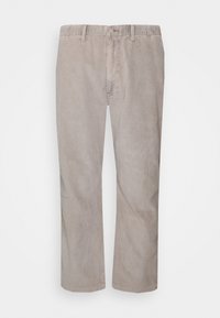 Béžové kordové kalhoty se střihovým designem rovného nohu, zdobené vertikálními pruhy a klasickým pasem s knoflíkovým zapínáním.