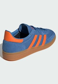 Blue sneaker with orange stripes, textured suede upper, rubber sole, and cushioned tongue. Features a logo on the side and contrasting heel.