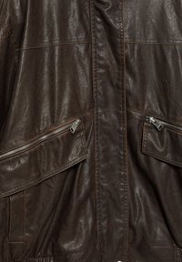 Giacca di pelle marrone con finitura testurizzata, due tasche sul petto con zip e un design del colletto liscio.