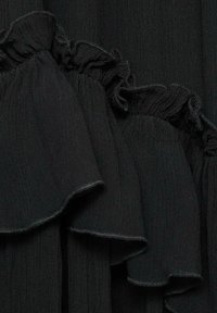 Black fabric featuring ruffled edges and a textured surface. The material has a subtle sheen with fine pleats running vertically.