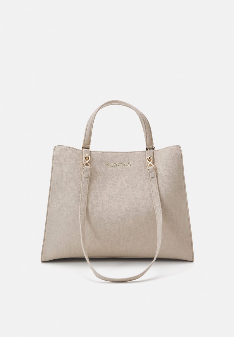 Beige teksturēta ādas soma ar divām īsām rokturiem un noņemamu plecu siksnu. Tajā ir zelta piederumi un iegriezts logo.