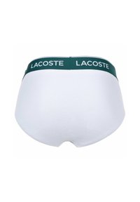 Witte katoenen slips met een groene elastieken tailleband met het "LACOSTE" logo in het wit, een gladde textuur en een afgerond ontwerp aan de achterkant.