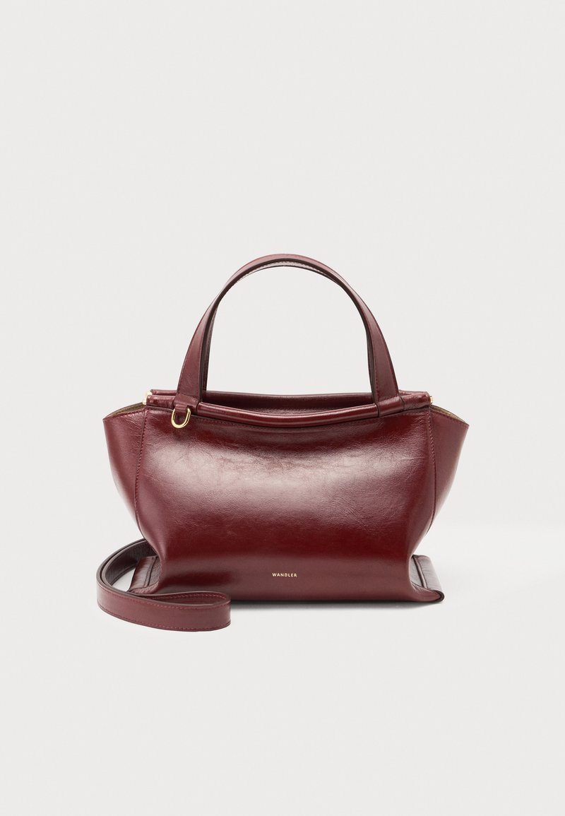 Sac à main en cuir rouge foncé avec doubles poignées supérieures, bandoulière amovible, ferrures dorées et nom de la marque Wandler au centre avant.
